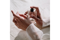 A girl spraying perfume on her wrists.